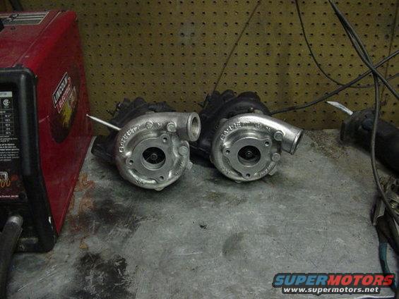 Two Garrett turbochargers on a workbench next to a red Lincoln Electric welder