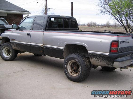 Silver and black Dodge pickup truck, lifted with off-road tires, seen from the side