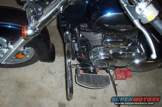 Close-up of a motorcycle's engine, front wheel, and handlebars. It's dark blue with chrome accents