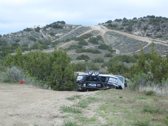 Off-road vehicle on its side with a custom bumper and auxiliary lights