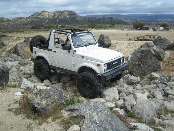 1987 Suzuki Samurai on rocky terrain, with a spare tire mounted on the back