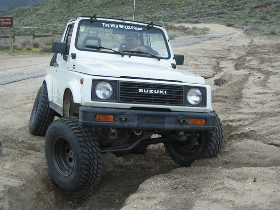 White 1987 Suzuki Samurai with large tires on a dirt trail