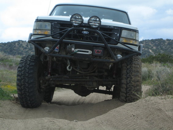 White Ford truck with winch and off-road lights, front view, lifted suspension, large tires