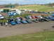 2001 Ford Fiesta - An outdoor gathering features a variety of vehicles parked near food vendors and a large grassy area.