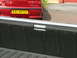1970 Ford Ranchero - A red sedan is visible behind the bed of a pickup truck, showing its rear bumper and license plate.