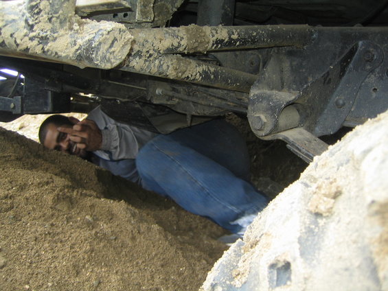 Person giving the finger from underneath a dirty vehicle chassis
