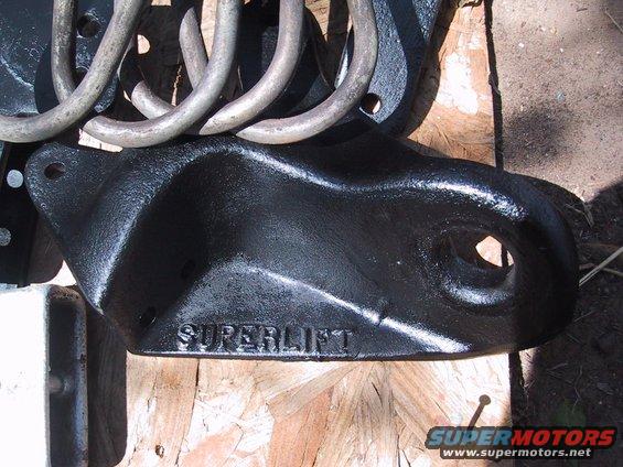 Black metal suspension bracket with "SUPERLIFT" embossed, next to silver coil springs