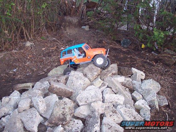 Orange and blue remote control rock crawler on a pile of rocks