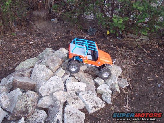 Orange RC Jeep with blue roll cage on rocks