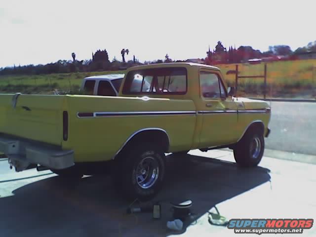 Yellow pickup truck parked outside, another white vehicle behind it