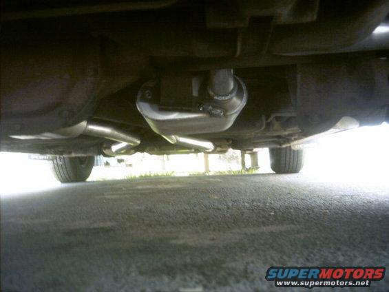 Underside view of a vehicle's exhaust system with a new muffler and dual pipes