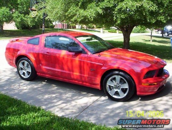 Red Ford Mustang parked on a driveway, 3/4 front view