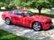 2006 Ford Mustang - A red Ford Mustang is parked on a driveway with trees in the background.