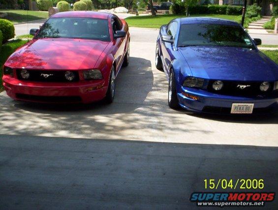 2006 Ford Mustang GT in Torch Red and another in blue parked side-by-side on a driveway