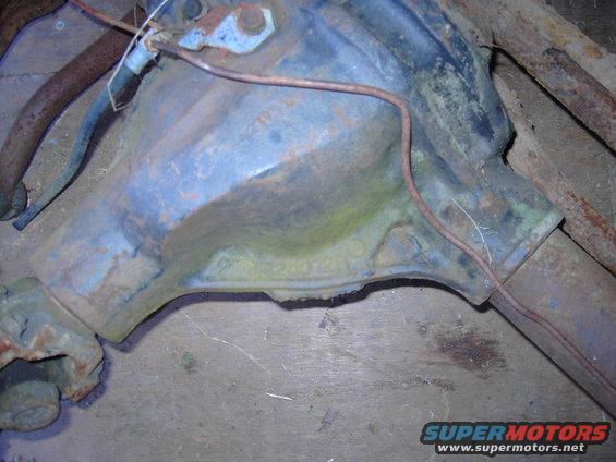 Close-up of a blue differential housing with some rust and a copper line running across it. Part number visible