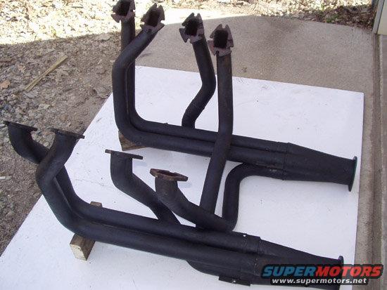 Two black exhaust headers on a white surface