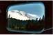 1979 Ford Bronco - A scenic view of a snow-capped mountain and forest is captured in the reflection of a vehicle's side mirror.