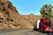 1979 Ford Bronco - A red semi-truck and trailer travels down a highway beside a mountain landscape.