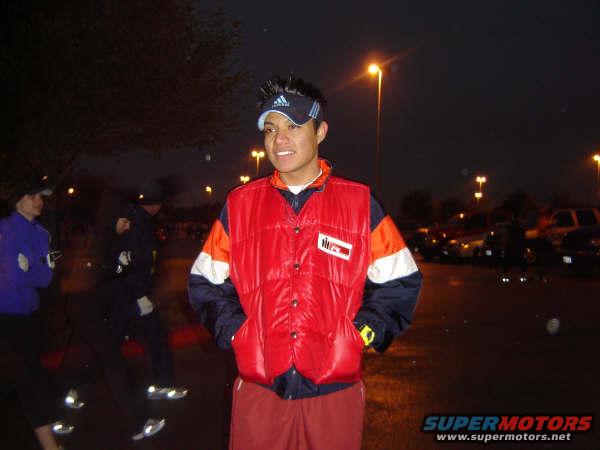 People in a parking lot at night with cars in the background