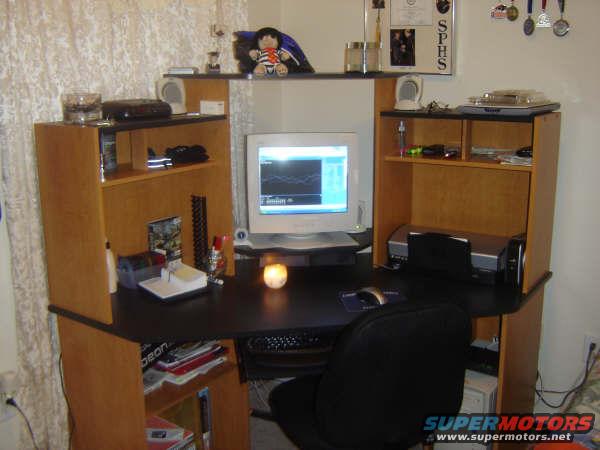 Desk setup with a CRT monitor, printer, and shelves holding various items