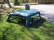 1996 Ford Bronco - A detached truck bed cap rests on a grassy lawn with trees and a gravel driveway in the background.