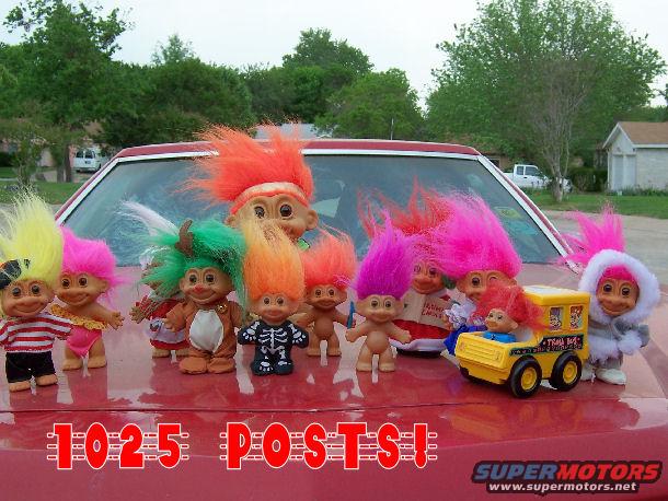 Troll dolls on red car hood with text '1025 POSTS!'