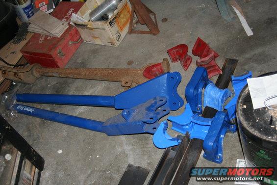 Blue metal parts and a rusty exhaust pipe on a concrete floor