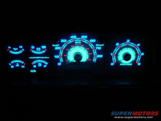 Dashboard gauges with blue glowing needles and indicators, including speedometer and tachometer