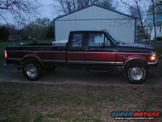 Side view of red and black pickup truck with chrome trim and toolbox in bed
