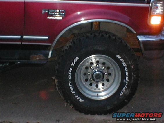 Close-up of a red Ford F-250 truck's front wheel and fender. BFGoodrich All-Terrain T/A tire on a polished aluminum wheel