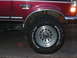 1979 Ford Bronco - A close-up shot focuses on the wheel and fender of a red Ford F-250 truck, highlighting its off-road tire.