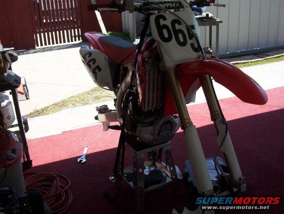 Red dirt bike with number 665 on front, on a stand