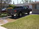 2006 Honda CR250R - A gray Ford F-150 pickup truck is parked in a driveway, with a sedan visible in the background.