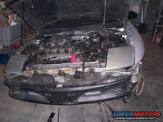 car with hood up, showing engine and front bumper removed