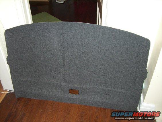 Dark gray carpeted rear cargo area trim panel with a rectangular cutout
