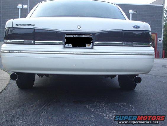Rear view of a white 1995 Ford Crown Victoria with tinted taillights and dual exhaust pipes
