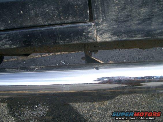 Close-up of a rusty metal running board bracket and chrome step on a truck