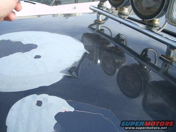 Dark hood with peeling paint and roof lights. Another vehicle is visible in the background