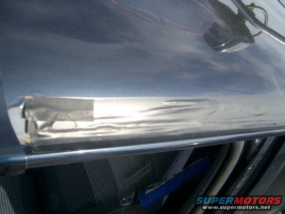 Close-up of a blue vehicle's interior trim with silver tape applied