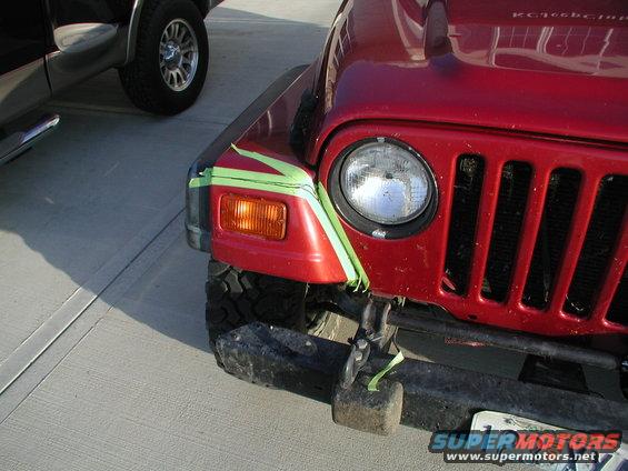 Red 1998 Jeep TJ front with green tape on fender and headlight