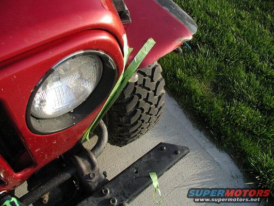 Red Jeep TJ front fender, headlight, and tire. Green tape on fender