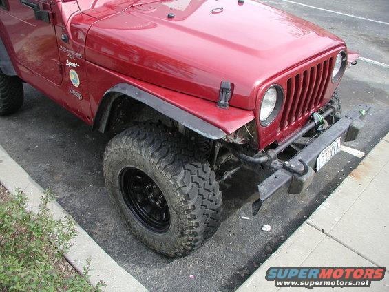 Red Jeep Wrangler with aftermarket bumper and off-road tires. Front bumper is damaged