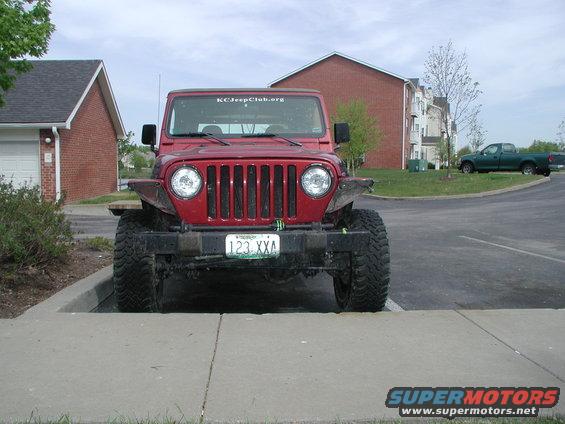 Red Jeep Wrangler parked on sidewalk, KCJeepClub.org sticker on windshield, license plate 123 XXA