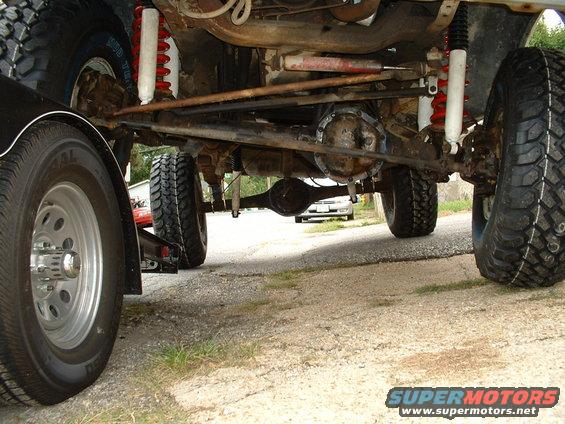 Undercarriage of a 4x4 vehicle with large tires, lifted suspension, and visible differential