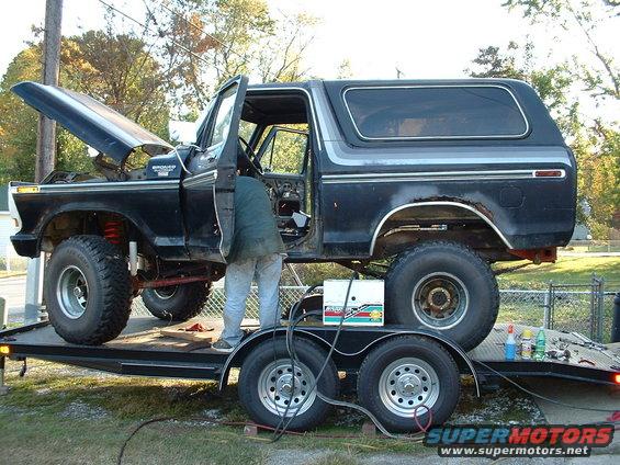 1978 Ford Bronco on trailer, hood open, door ajar, being worked on