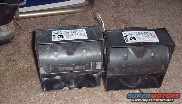 Two black Whelen siren speakers with caution labels