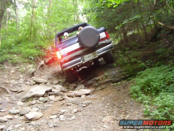 Rear view of a 1990 Ford Bronco navigating a rocky off-road trail