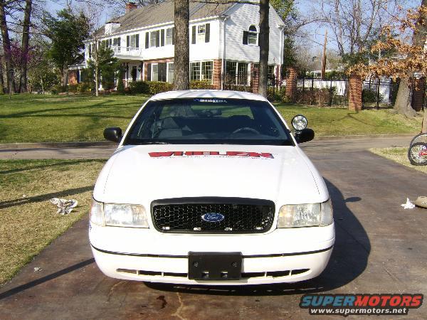 White Ford Crown Victoria, front view, with red lettering on windshield and a black grille