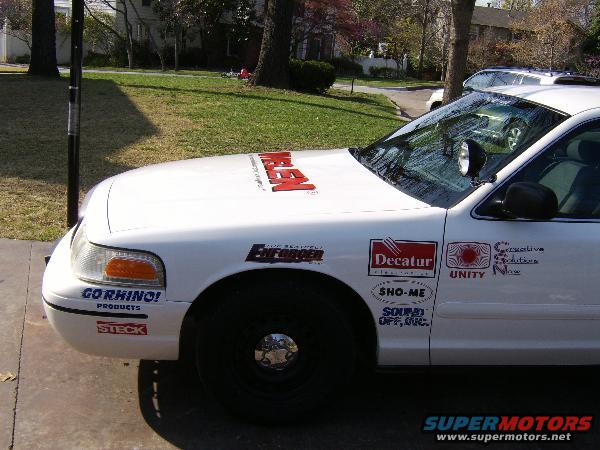 1999 Ford Crown Victoria police car with 'ENFORCER' and other decals on the hood and fender