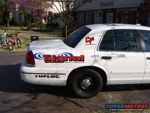 White sedan rear quarter view with 'Signal Vehicle Products' and 'Tufloc' decals